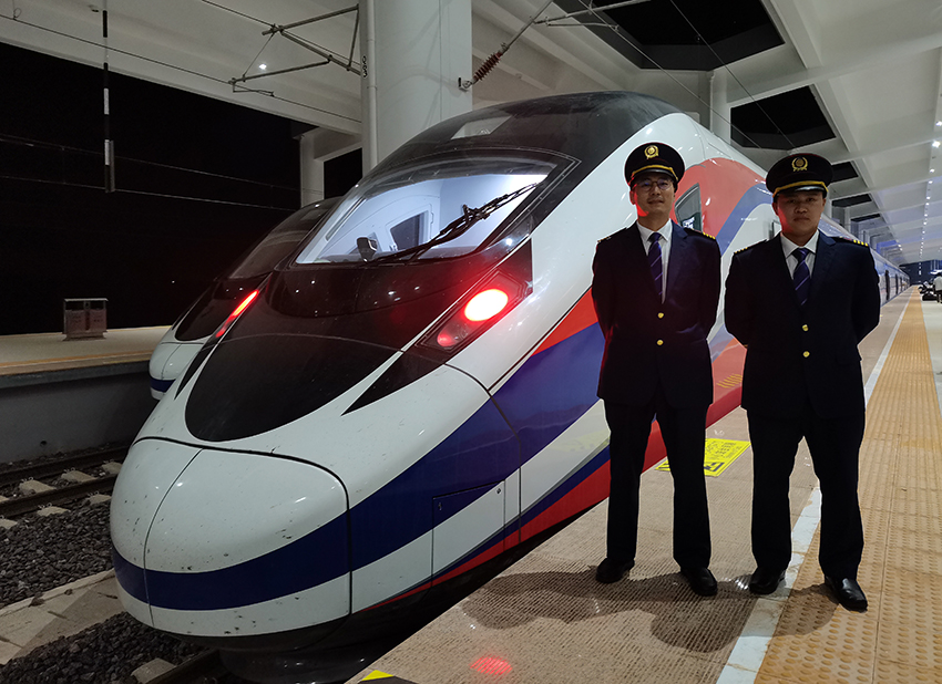 劉銀能(右一)與中國師父鄔俊鴻在動車組前合影。受訪者供圖